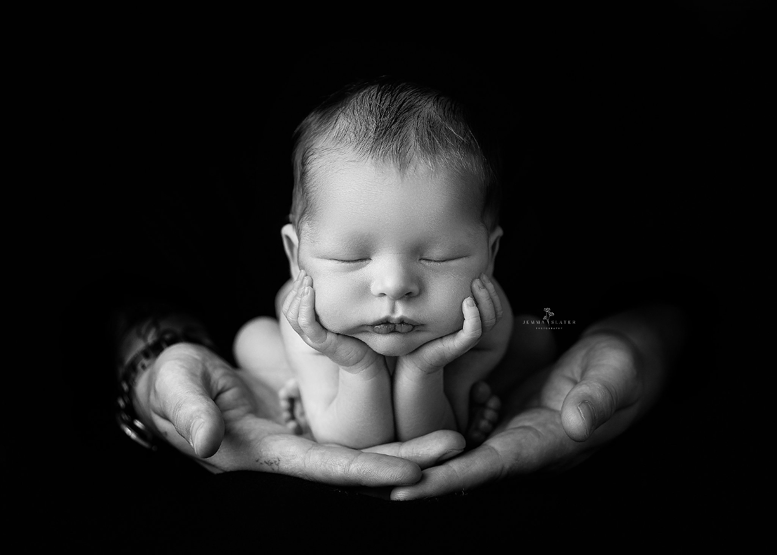 newborn baby in the froggy pose sat in fathers hands