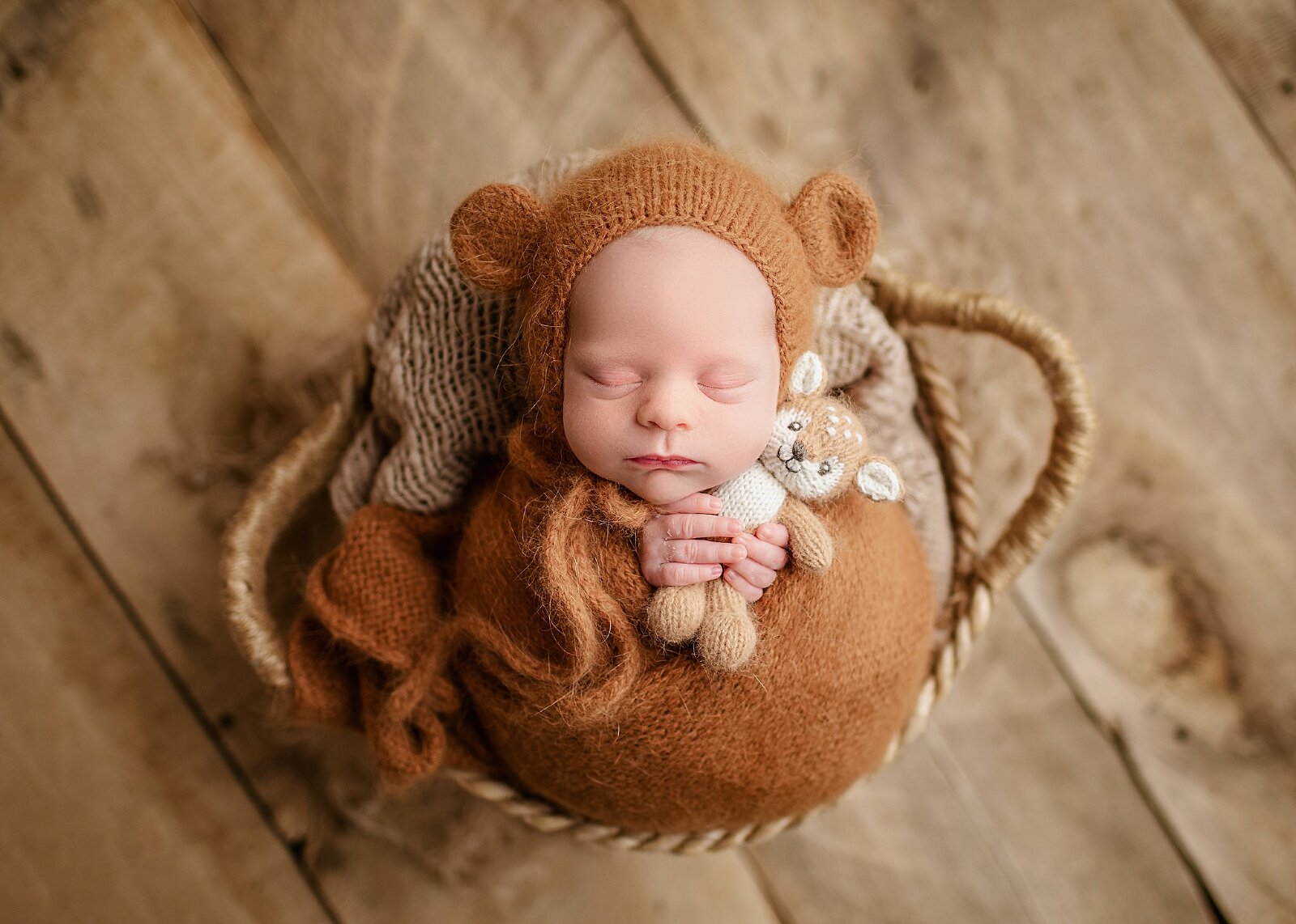 baby boy wearing a teddy bonnet wrapped in a bundle holding a teddy