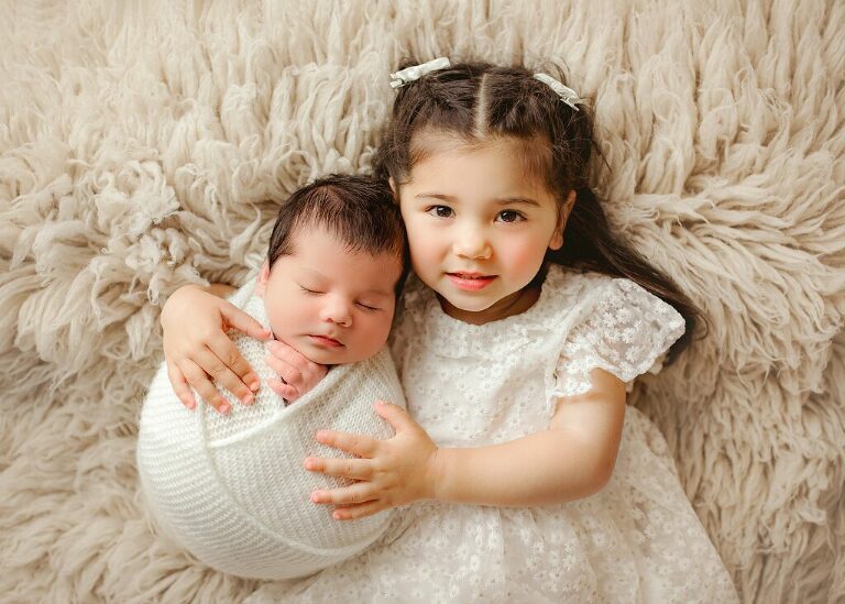 Sister holding new baby brother in arms
